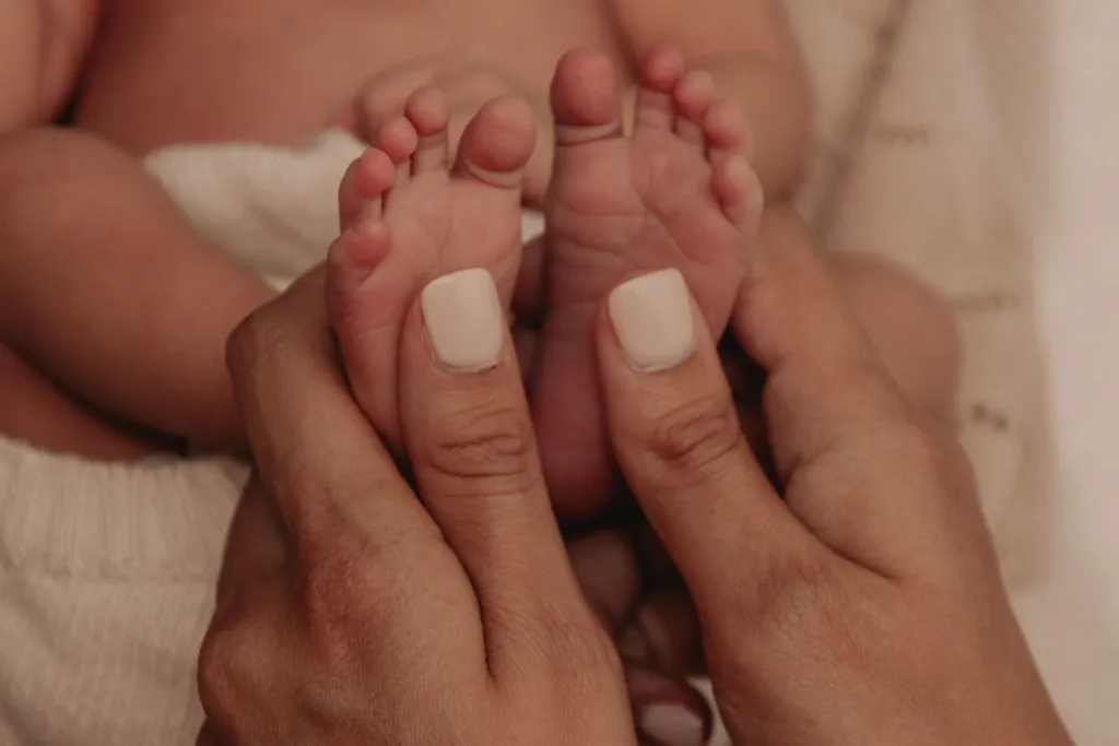 Mains d'un adulte tenant délicatement les petits pieds d'un nouveau-né