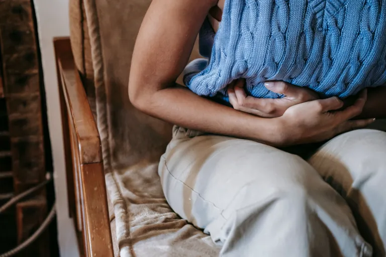 Personne assise dans un fauteuil, les deux mains serrées sur le ventre