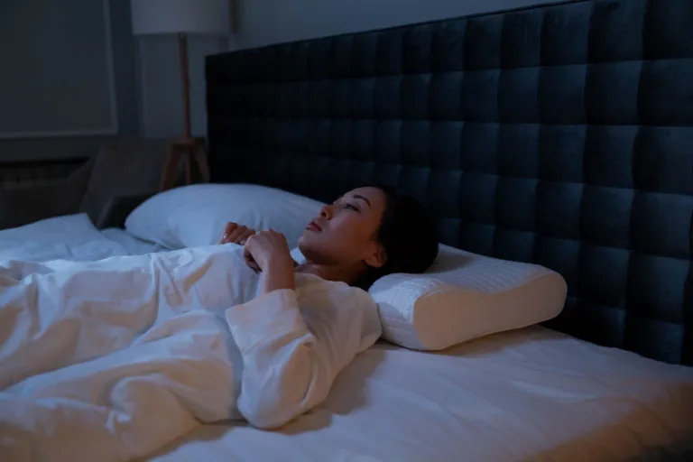 Femme allongée dans son lit la nuit, éveillée, le regard tourné vers le plafond