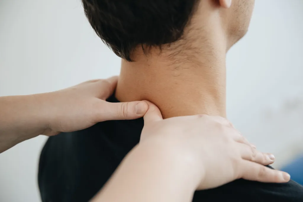 Mains d'un thérapeute posées sur la nuque et l'épaule d'un patient assis